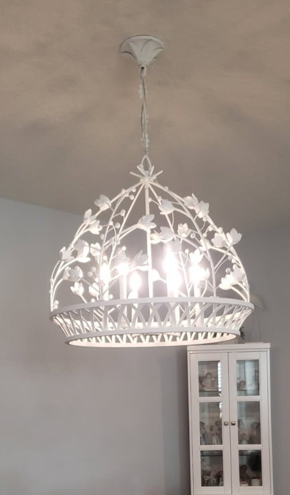 This decorative white chandelier looks even more beautiful when it is on and also compliments the white cabinet in the background.
