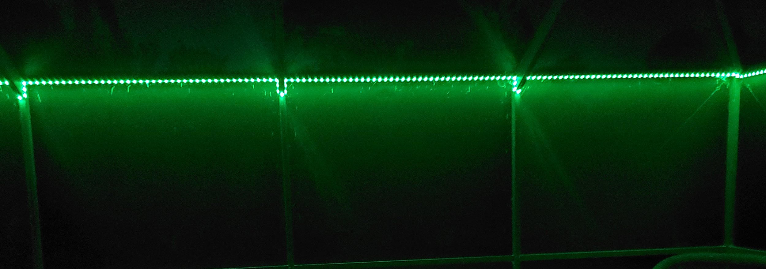 Green LED strip lights illuminating a dark outdoor patio area..