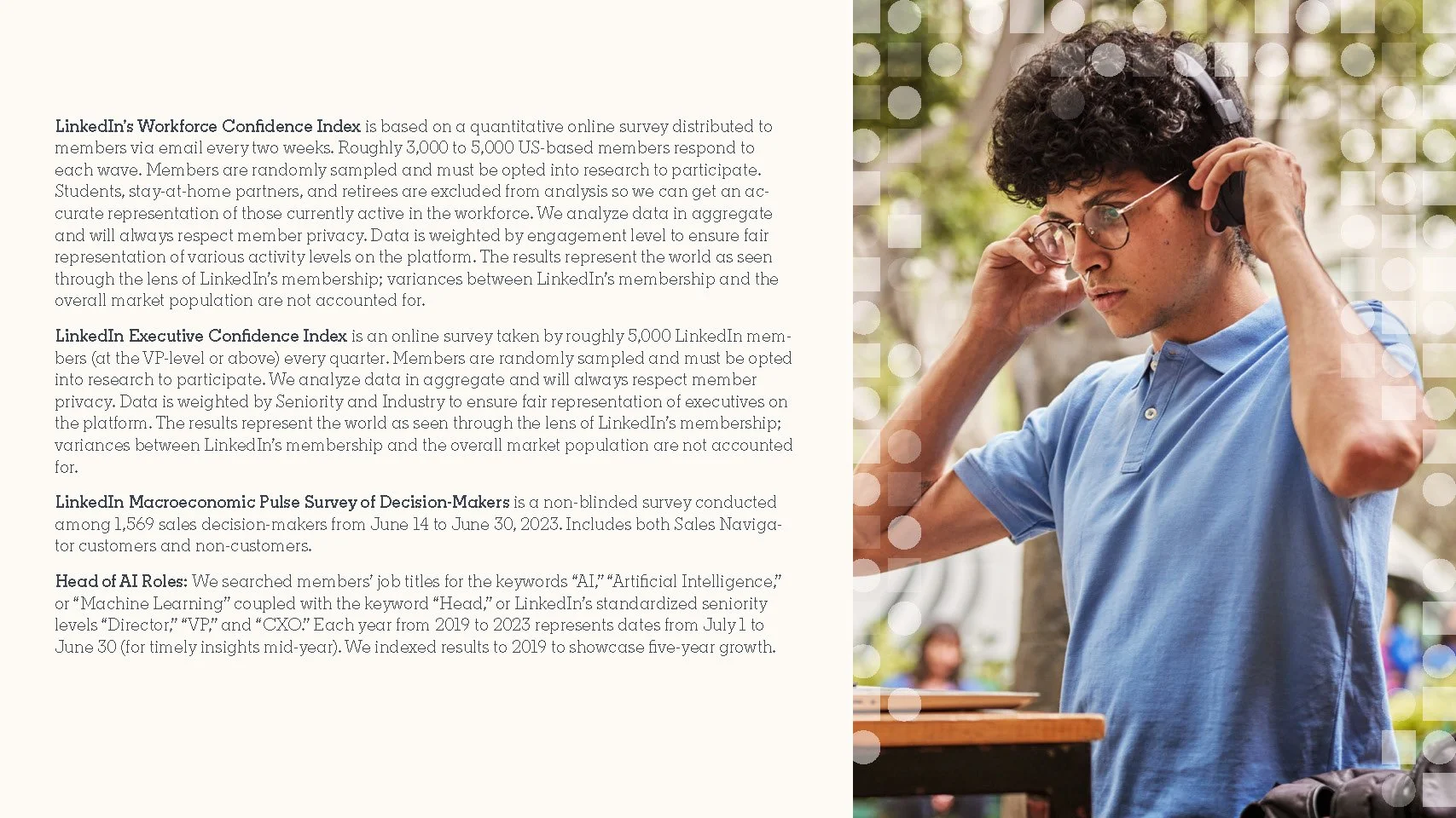 Young man with curly hair and glasses listening to headphones outdoors.