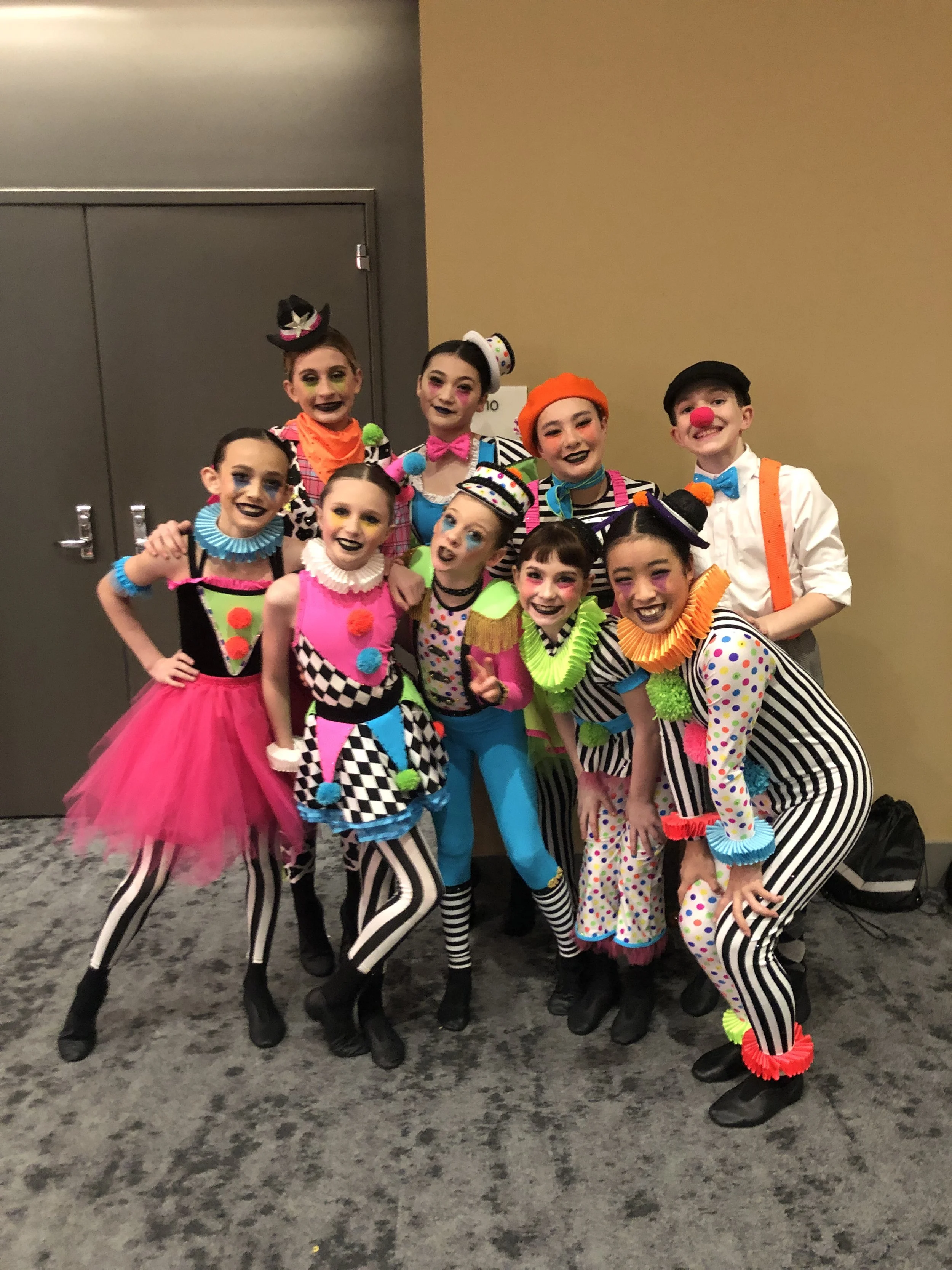Group of children dressed as clowns posing together indoors.