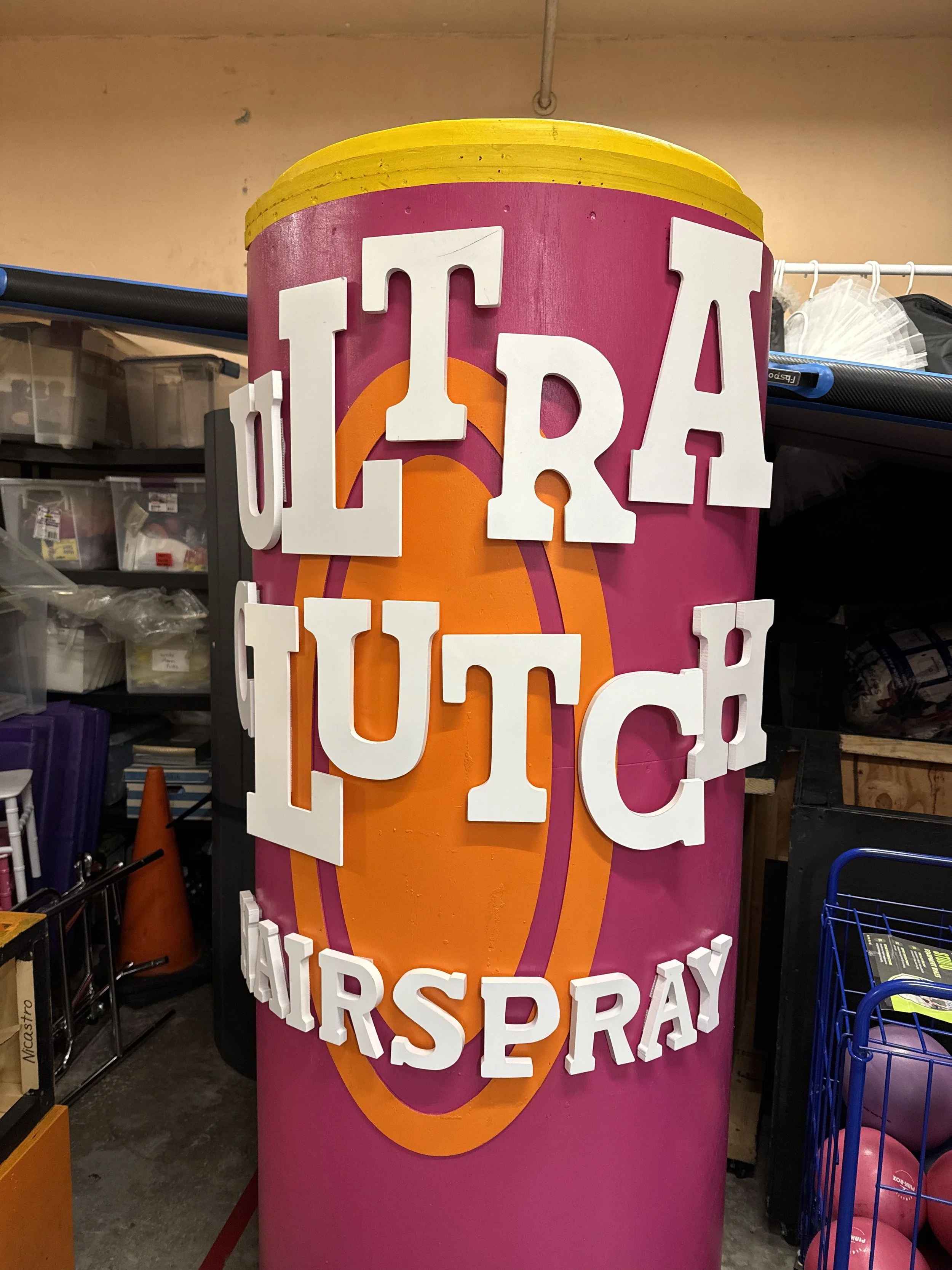 Colorful standing sign with large white block letters spelling 'AREA', against a pink background with an orange and purple logo or design, and additional white letters below.