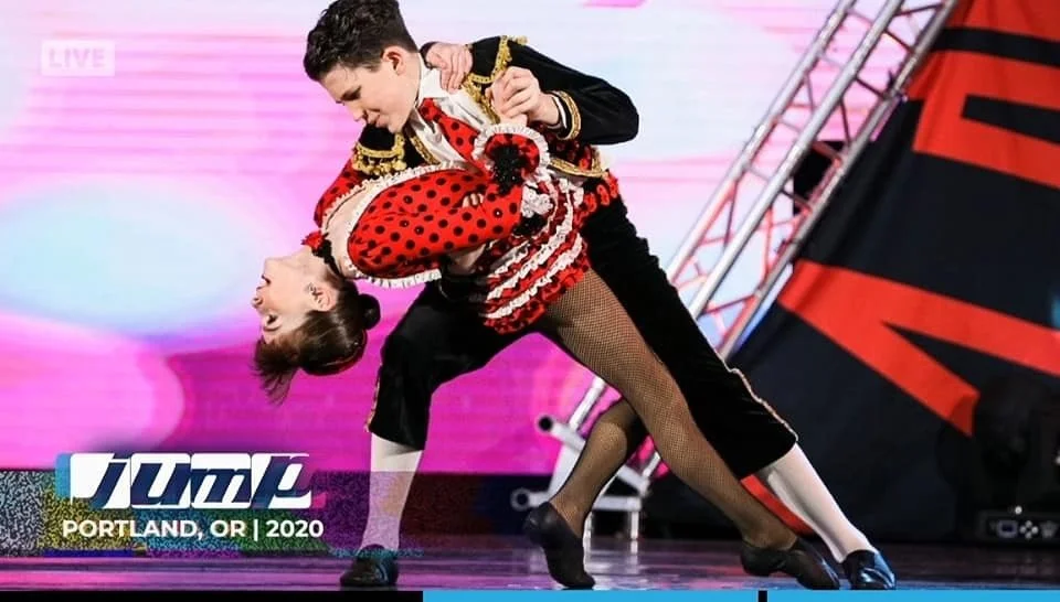 A male and female dancer performing a ballroom dance on stage at the 2020 Portland, Oregon competition.