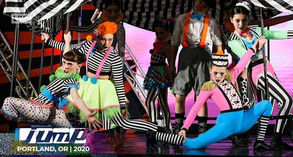 Group of performers dressed in colorful, whimsical circus costumes on stage with a pink background at the 2020 Pin Pals event in Portland, Oregon.