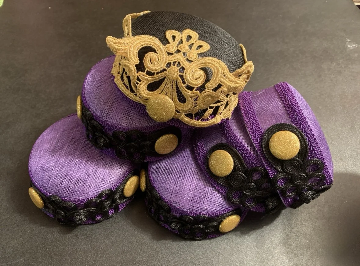 Decorative purple and black fabric objects with gold accents, resembling small wrapped gifts or ornaments.