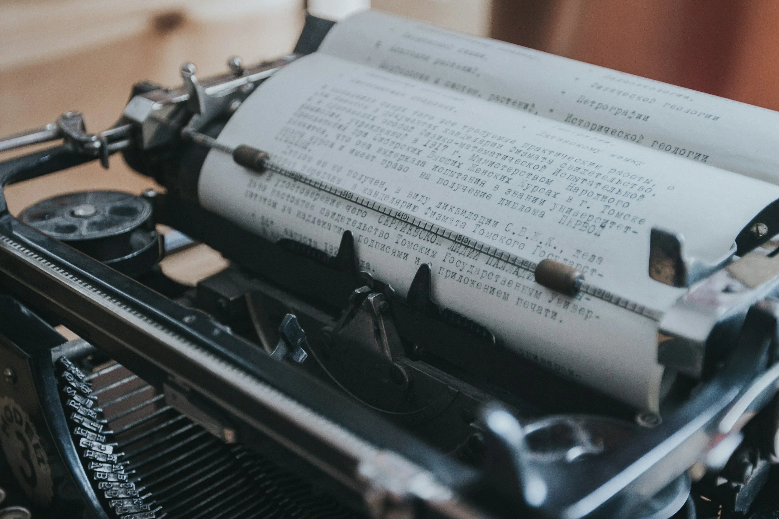 A vintage typewriter with a sheet of paper inserted, displaying text in Russian language.