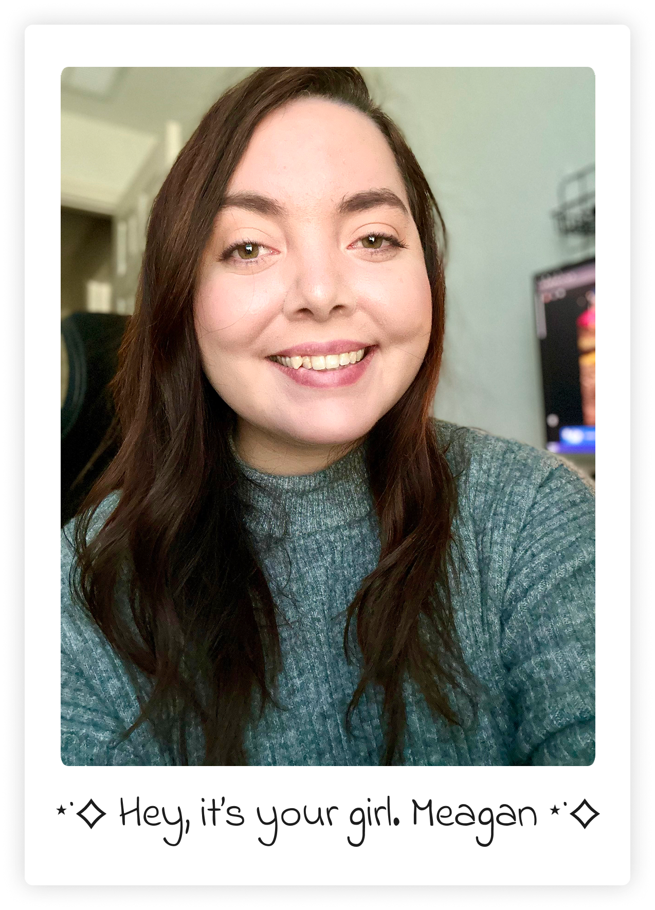 A woman with long brown hair and light-colored eyes smiling at the camera, wearing a gray sweater. In the background, there is a blurred room with a television visible. The image features a caption underneath that reads, "Hey, it's your girl. Meagan."