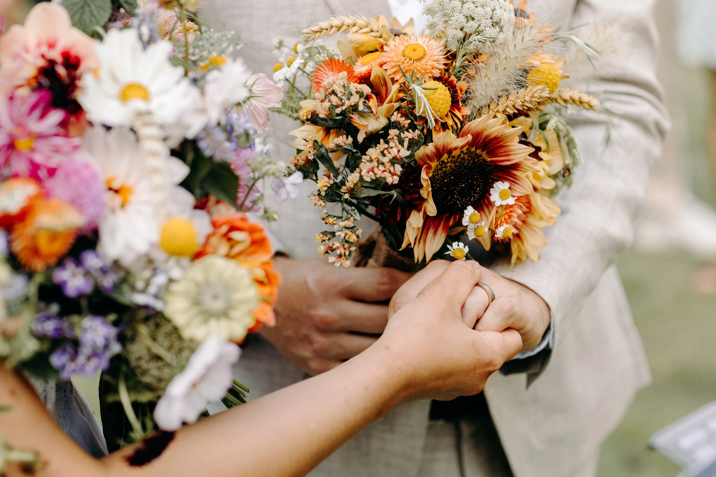 People exchanging flower bouquets at a celebration or wedding outdoors.
