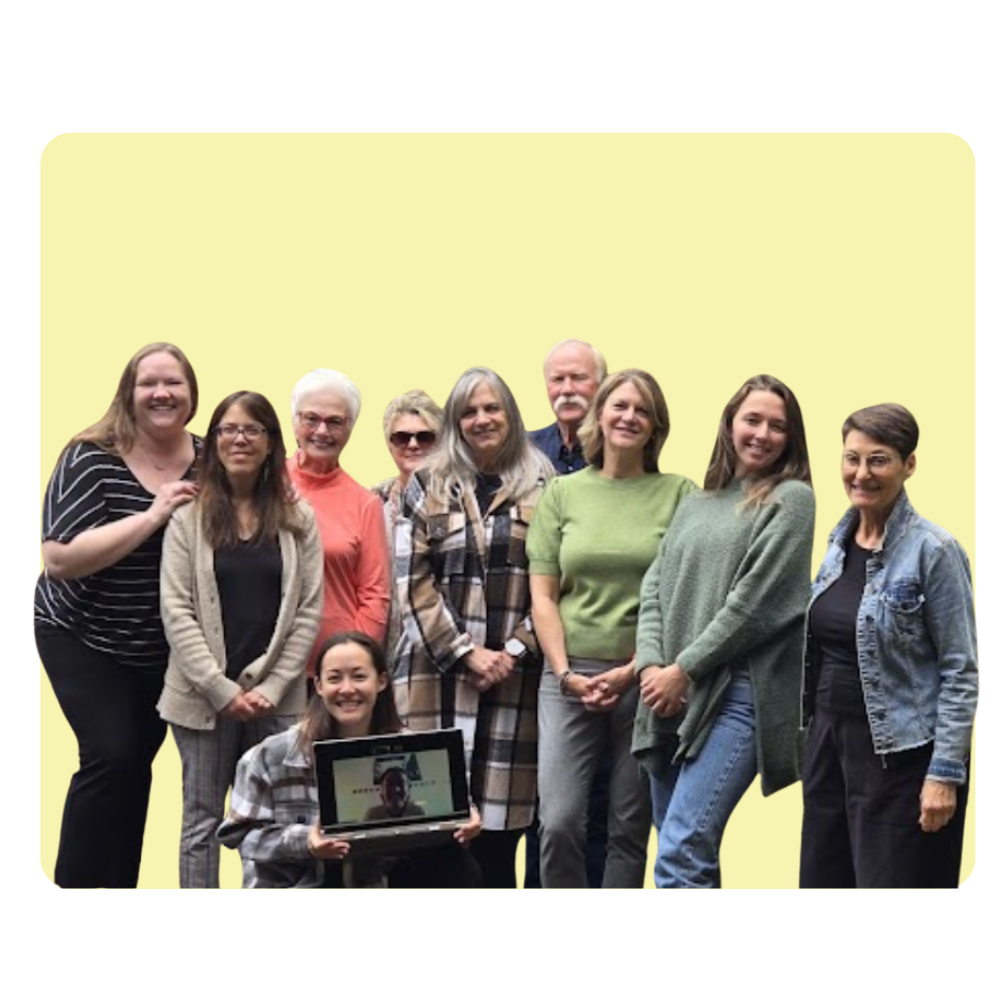 Group of ten diverse women and one young girl standing together against a light yellow background, some smiling and others with neutral expressions, with the girl holding a tablet showing a person’s face.