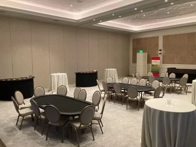 Empty event room with round tables and chairs, cocktail tables, and buffet stations.