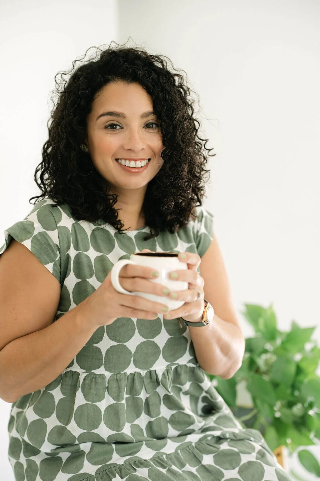 Christina Martin Kenny, nonprofit fundraising consultant, smiling and holding a white mug in a plant-filled space.