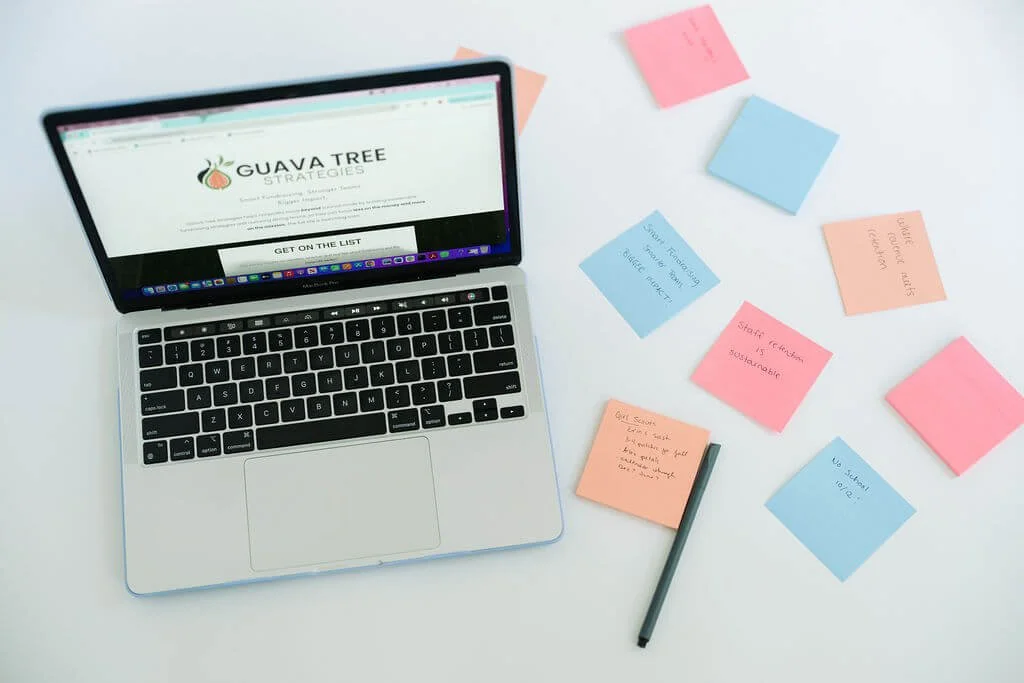 A laptop and colorful post-it notes on a white desk representing the planning work behind a nonprofit fundraising strategy.