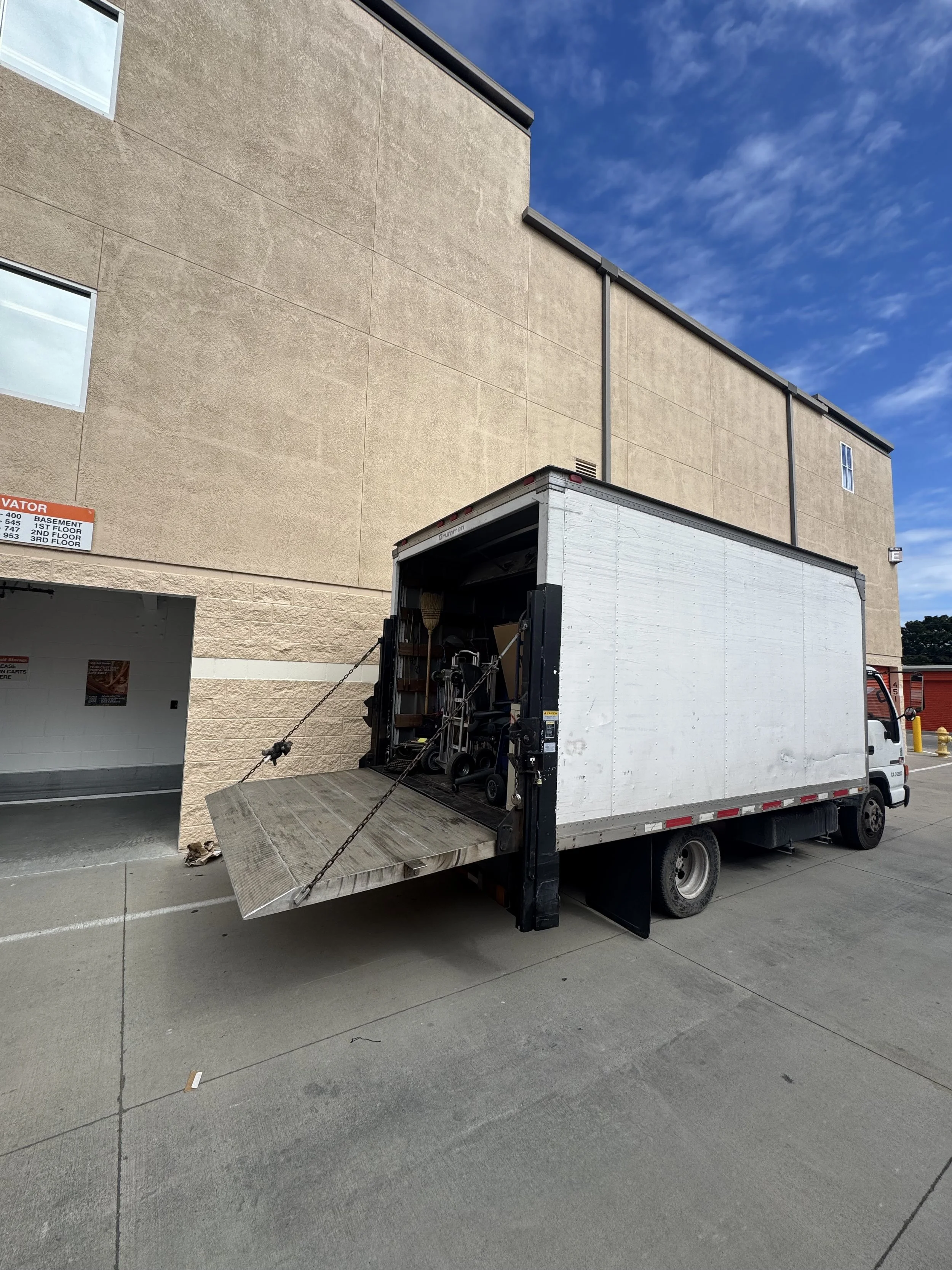 A modern house on a grassy hillside in front of snow-capped mountains during overcast weather.