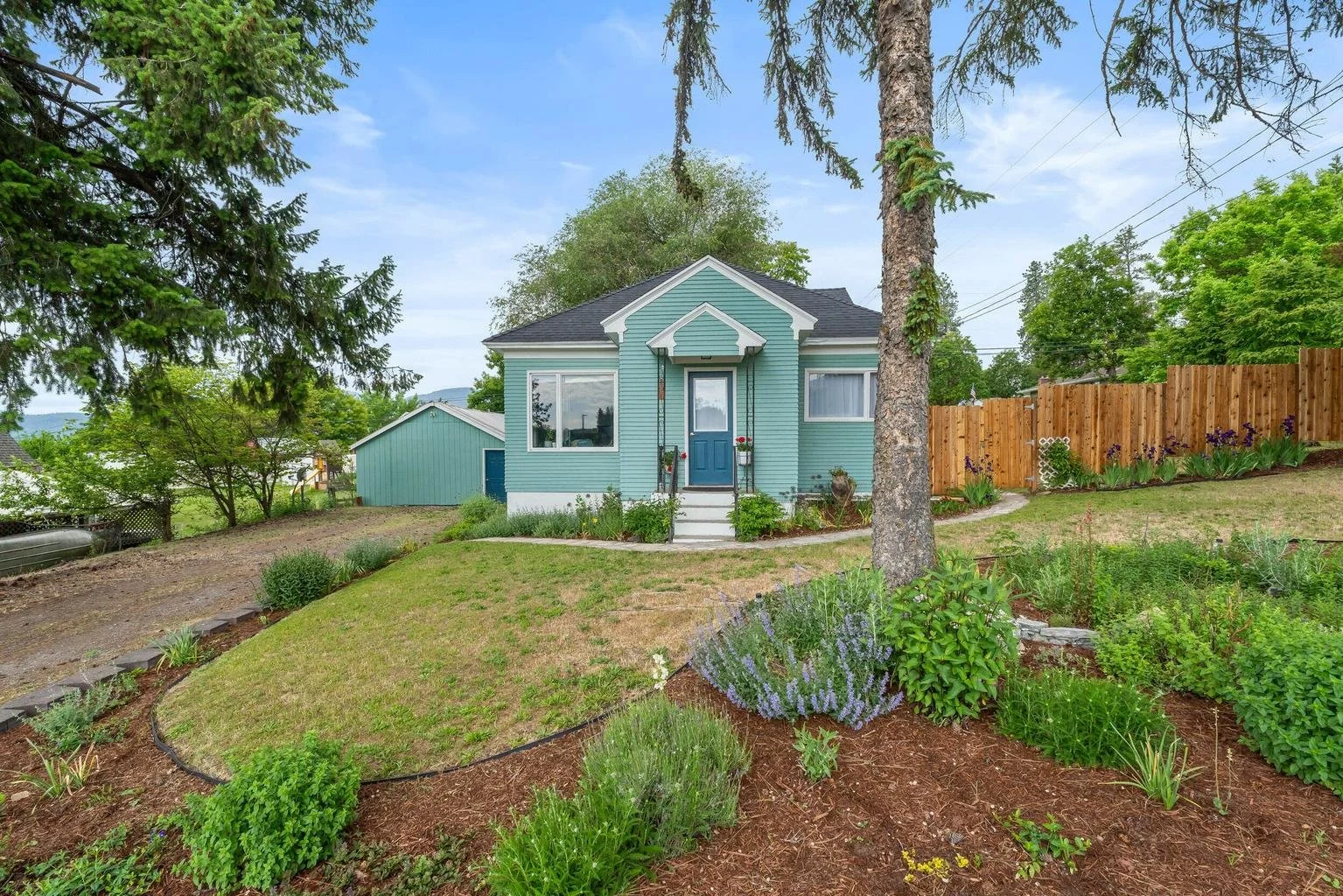 Charming cottage-style home sold at 697 S Hofstetter in Colville, WA 99114 featuring fresh exterior paint, landscaped front yard, mature trees, detached garage/shop, and inviting curb appeal in a peaceful Northeast Washington neighborhood. God is goo