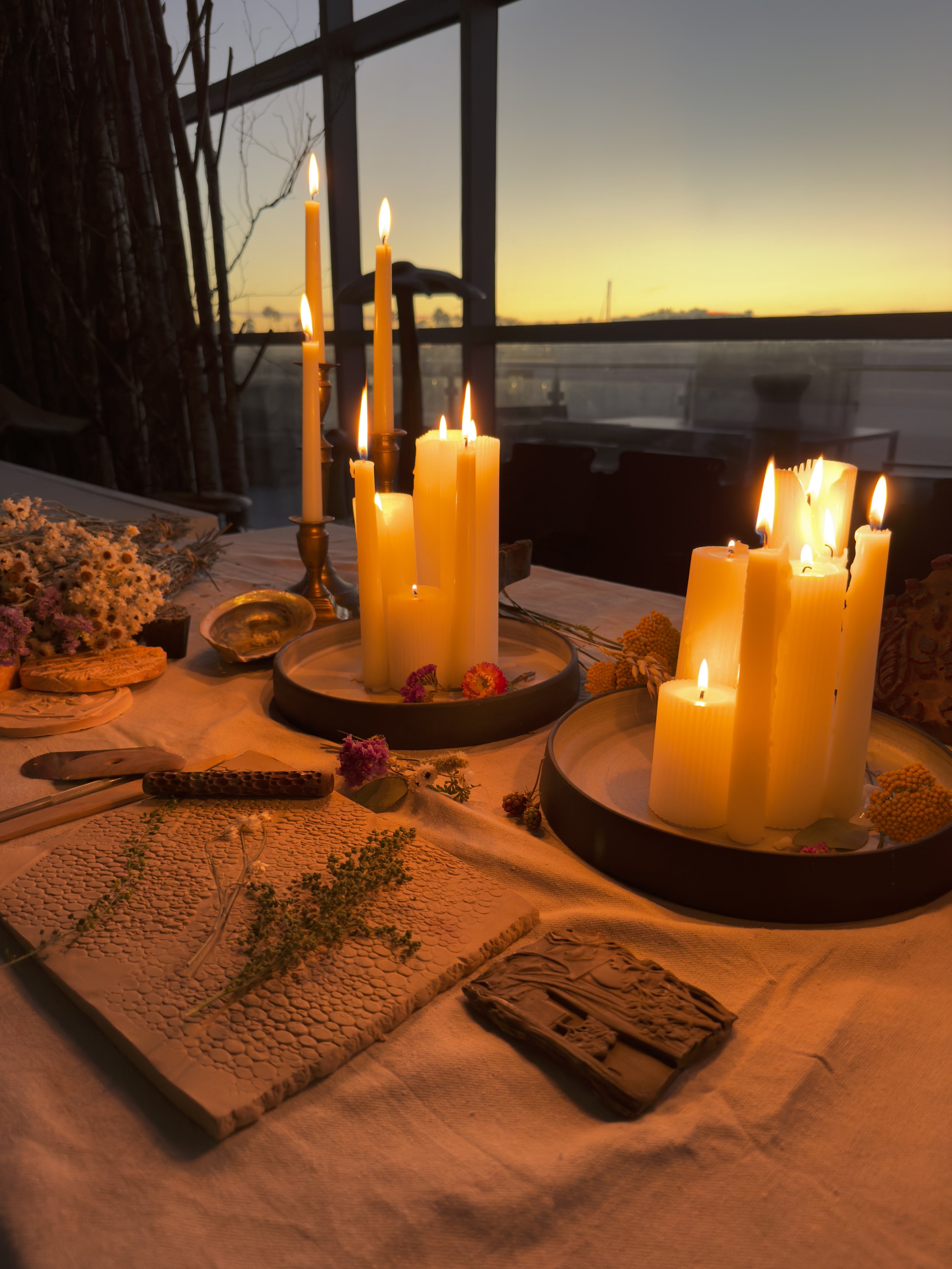 Table decorated with lit candles, flowers.Handbuilding class by candlelight. Pottery studio. Romantic vibe with ocean views .