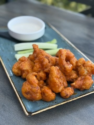 Fried chicken pieces with celery sticks and ranch dipping sauce on a blue ceramic plate