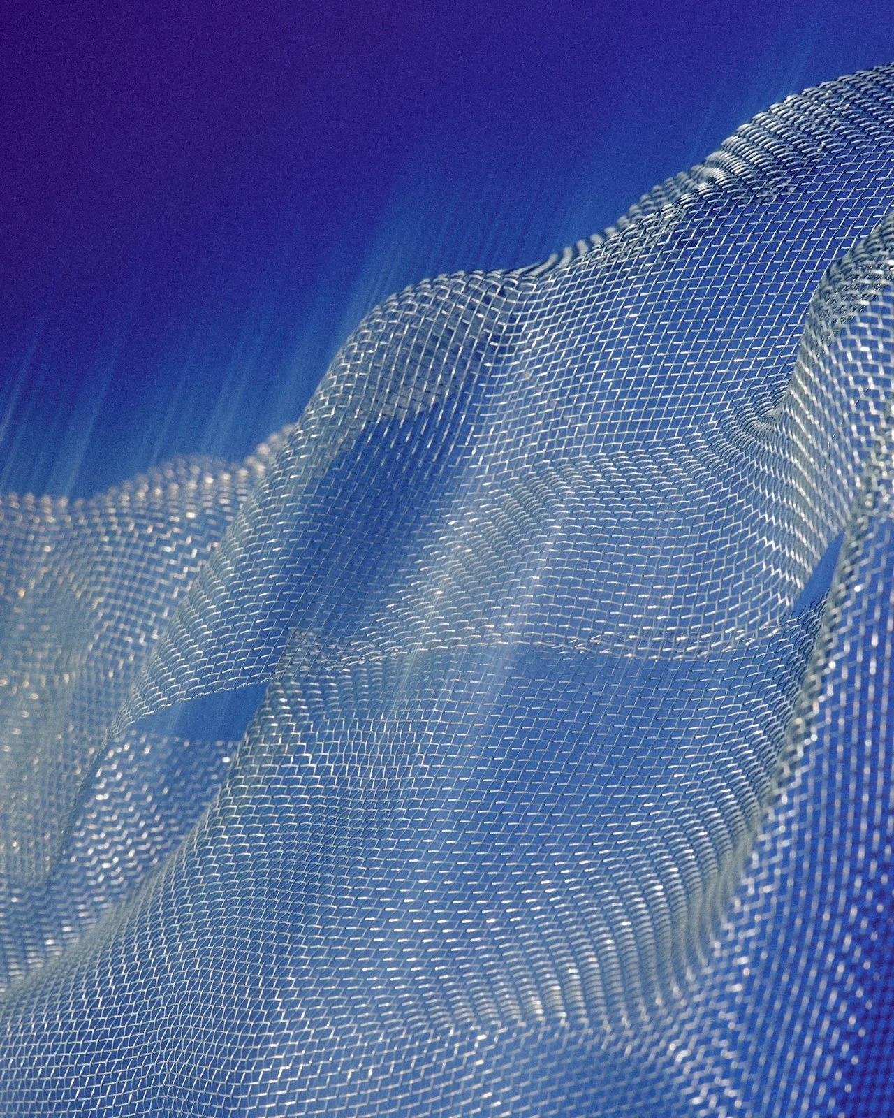 Abstract image of a mesh-like material with a blue gradient background, creating a wave-like effect.