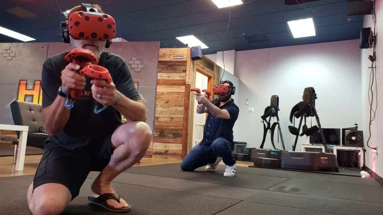 Two men crouching and aiming with VR controllers during an interactive virtual reality shooting game