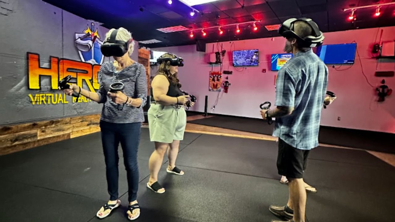 Group wearing VR headsets and holding motion controllers in the play area at HEROES VR Adventures.
