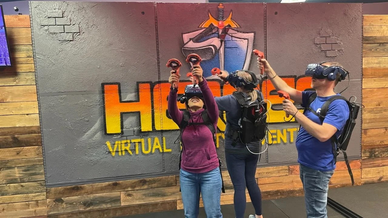 Group of adults playing a multiplayer VR game with headsets and motion controllers during a team activity.