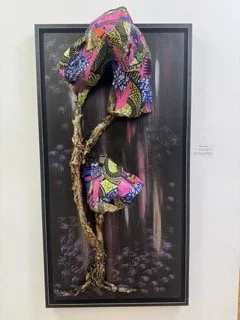 Mixed media art depicting a tree with colorful fabric leaves and a small matching purse hanging from one branch, framed on a black background.