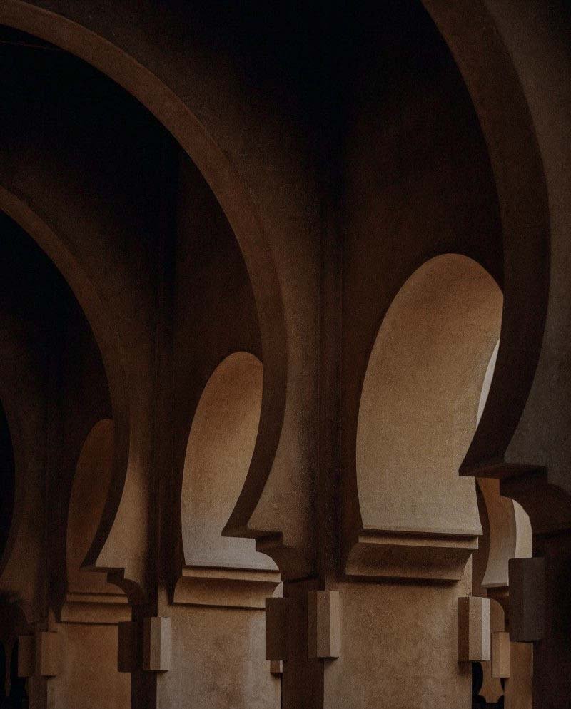 A series of arches with stylized face profiles carved into each column, creating a patterned architectural design.