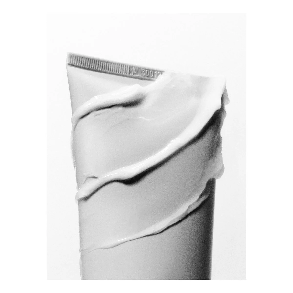 Close-up of a tube of cream with white cream oozing out and a silver cap visible at the top.