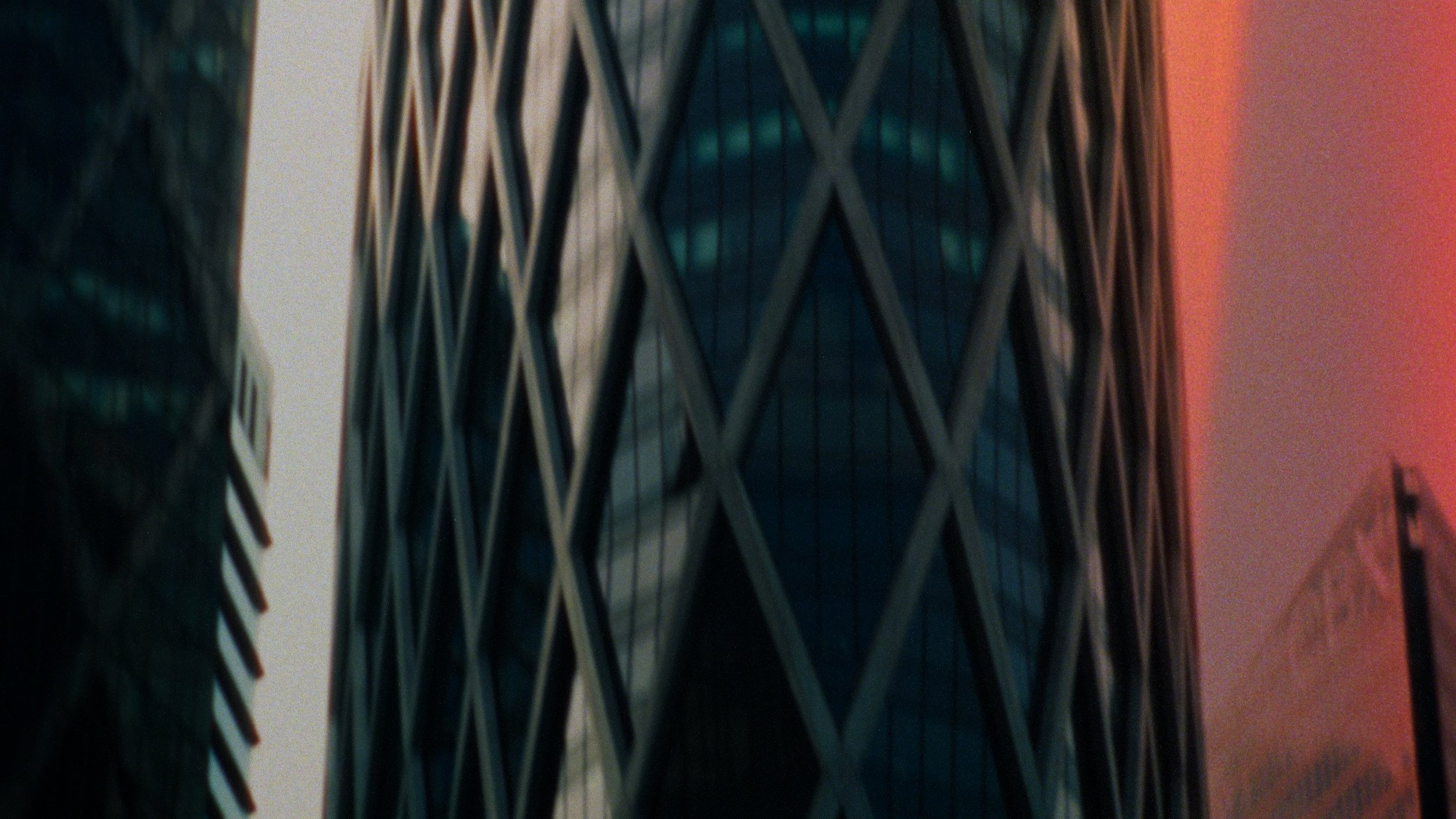 Close-up of a modern high-rise building with a crisscross geometric pattern on its facade, reflecting surrounding structures.