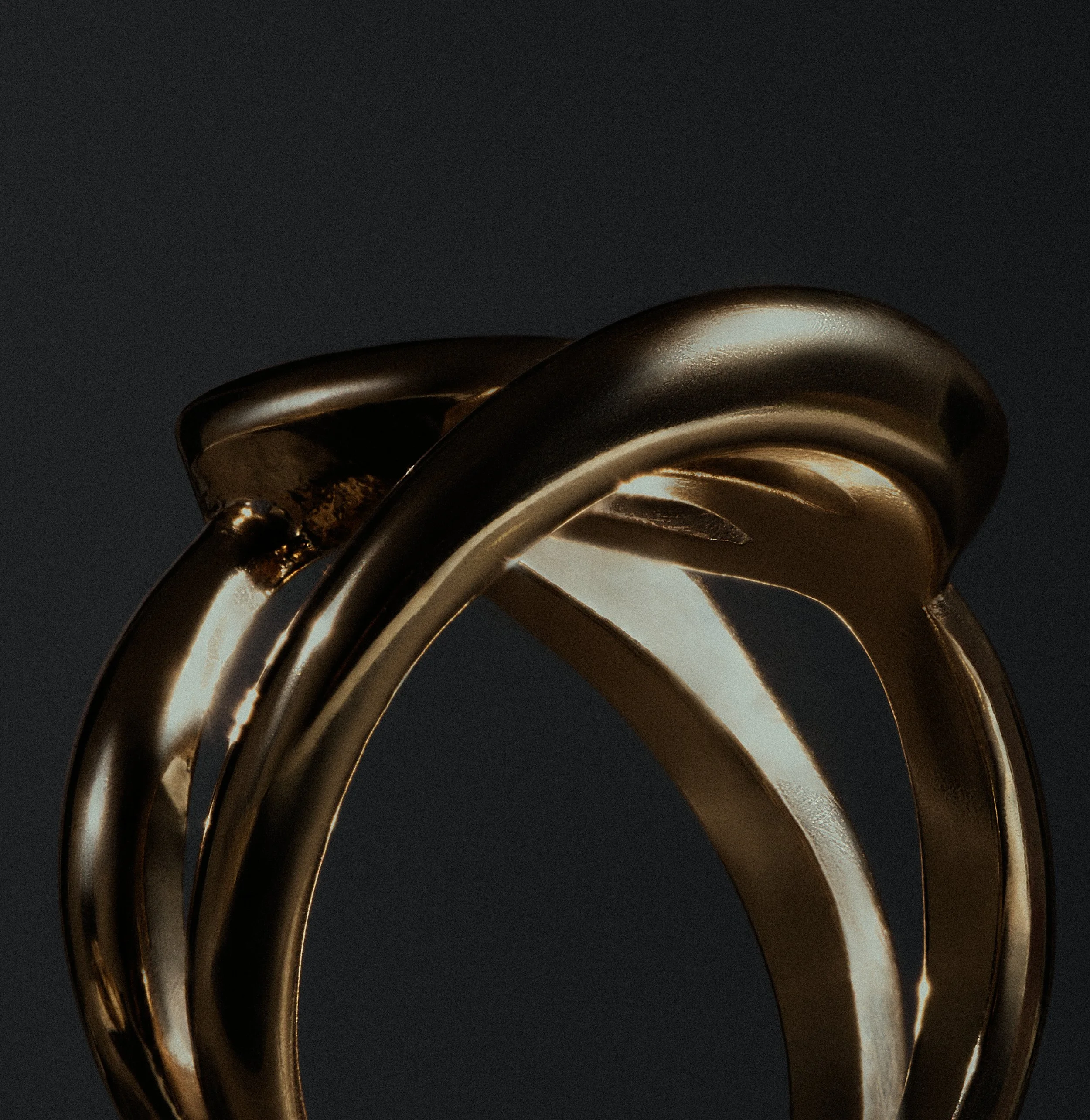 Close-up of intertwined gold rings against a dark background.