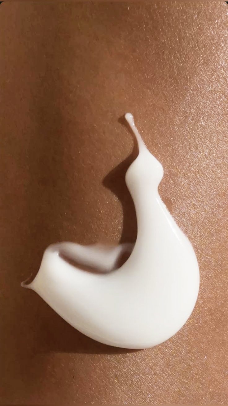 Close-up of a dollop of white cream or lotion on a smooth, copper-colored surface.