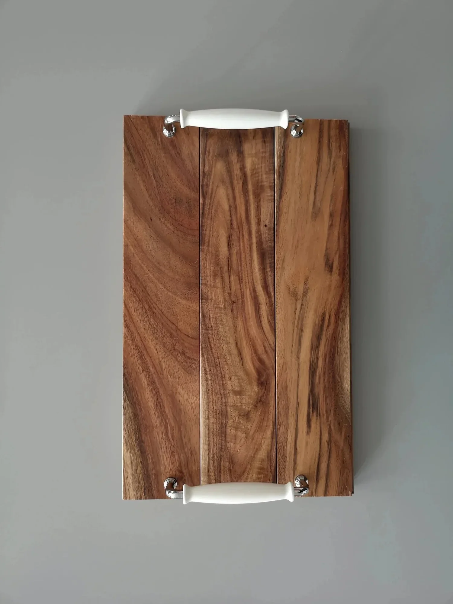 Wooden wall shelf with white ceramic handles mounted on a gray wall.
