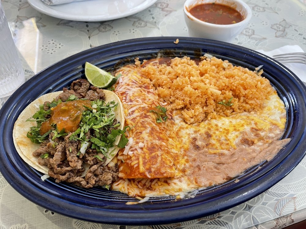 Plate of Mexican food with rice, cheese enchilada, beef taco, and salsa in the background.