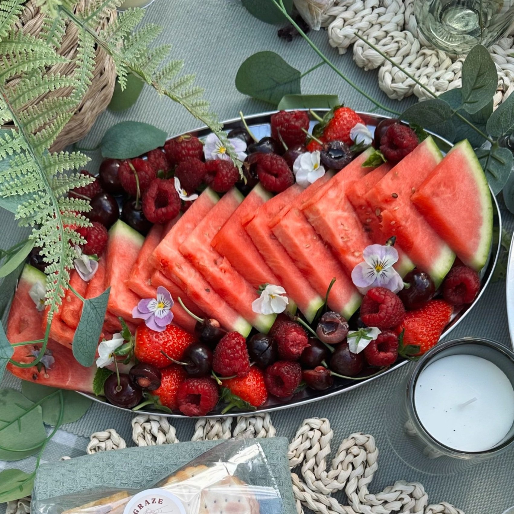 Red fruit grazing platter with watermelon, strawberries, raspberries, cherries, blueberries, and blackberries on a serving tray.