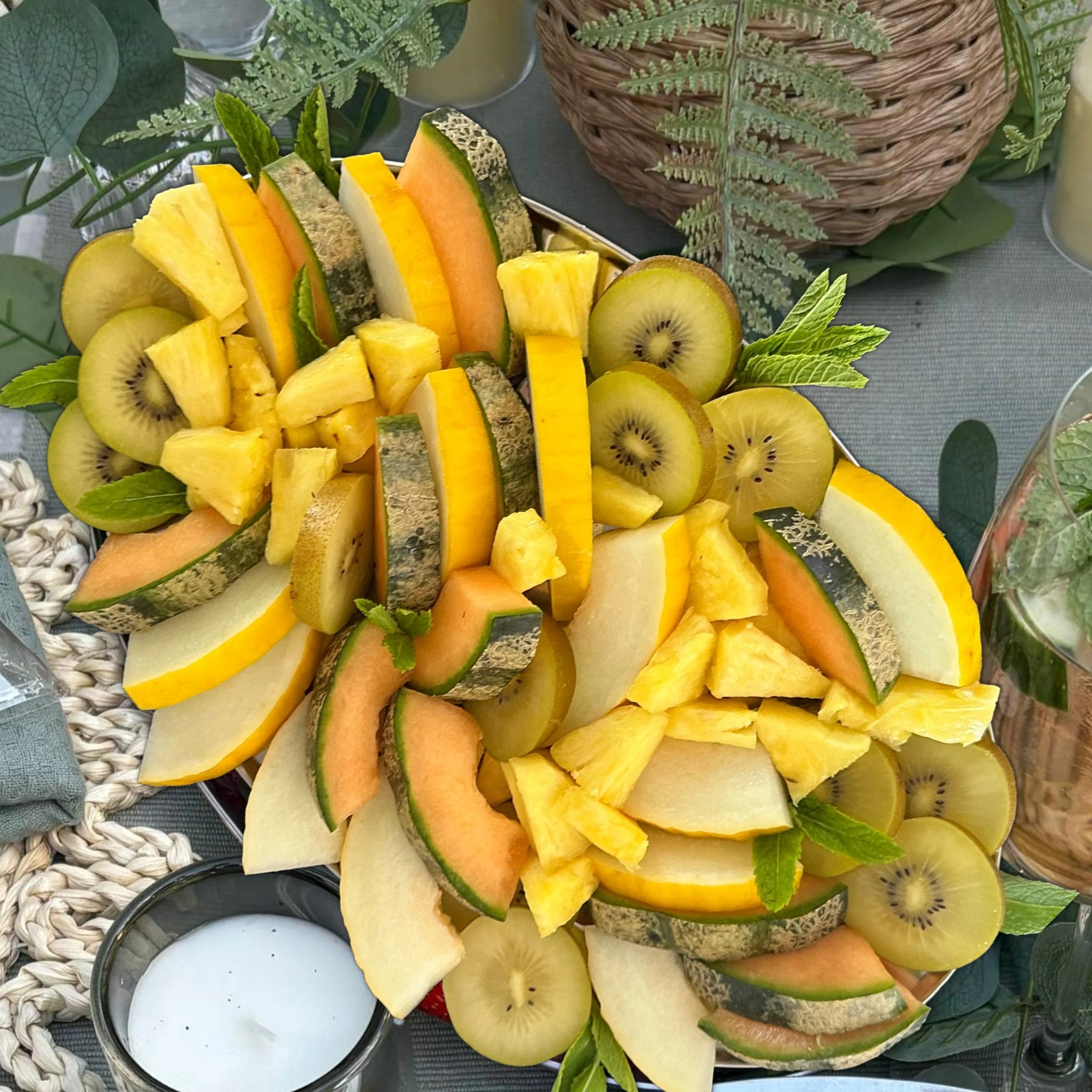 Yellow and tropical fruit grazing platter with melon, apple, pineapple, orange, golden kiwi, and mango on a serving tray.
