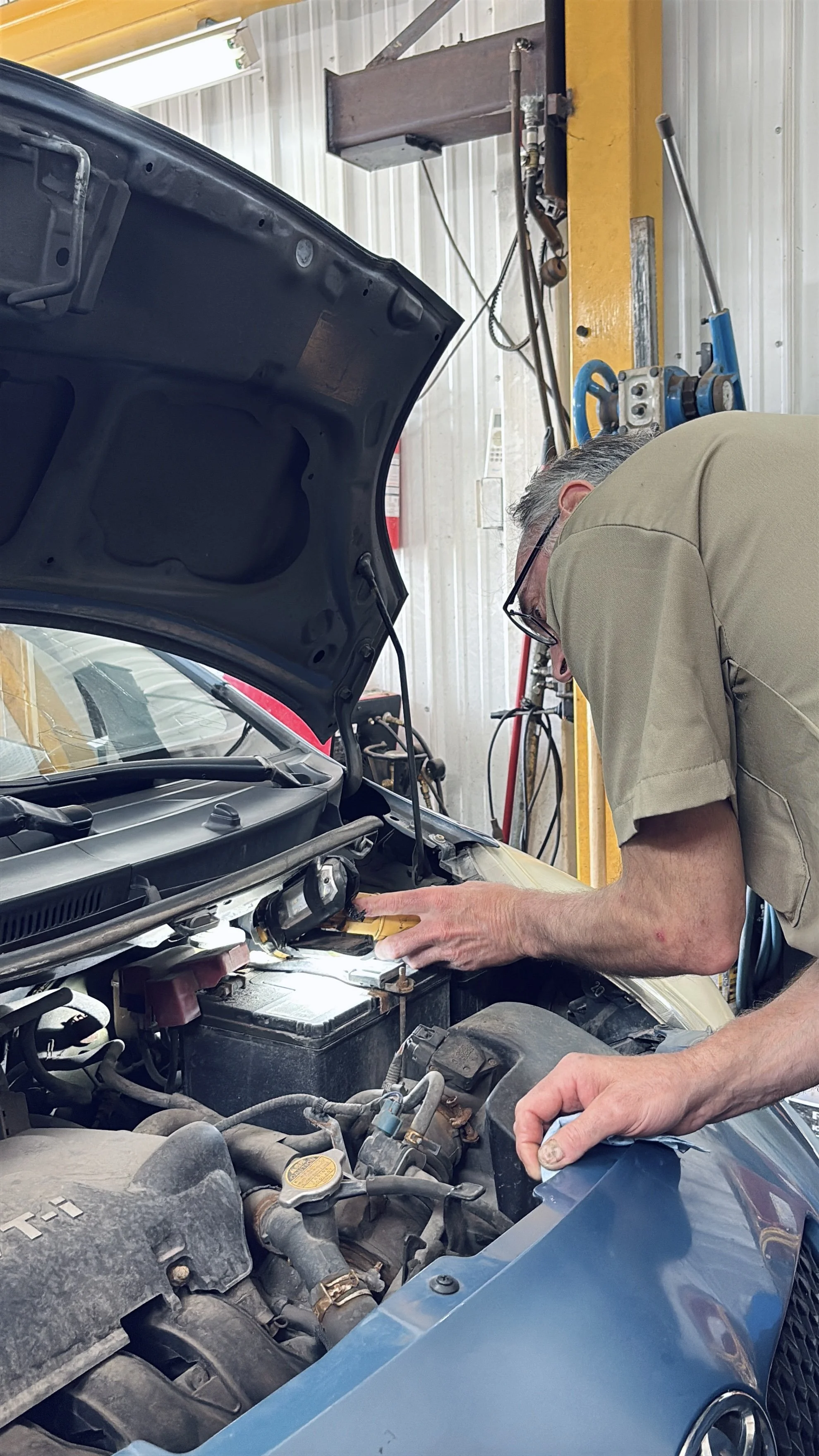 Un mécanicien examine le moteur d'une voiture dans un atelier de réparation automobile.
