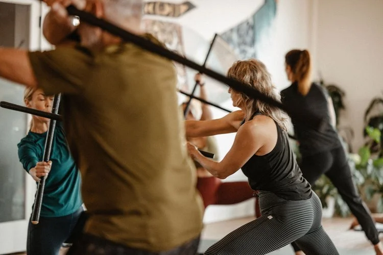 People practicing martial arts with sticks in a combat training session.
