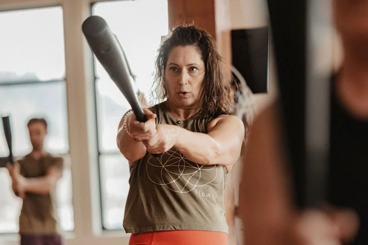 Woman holding a kettlebell with both hands during a fitness class, focused and determined.