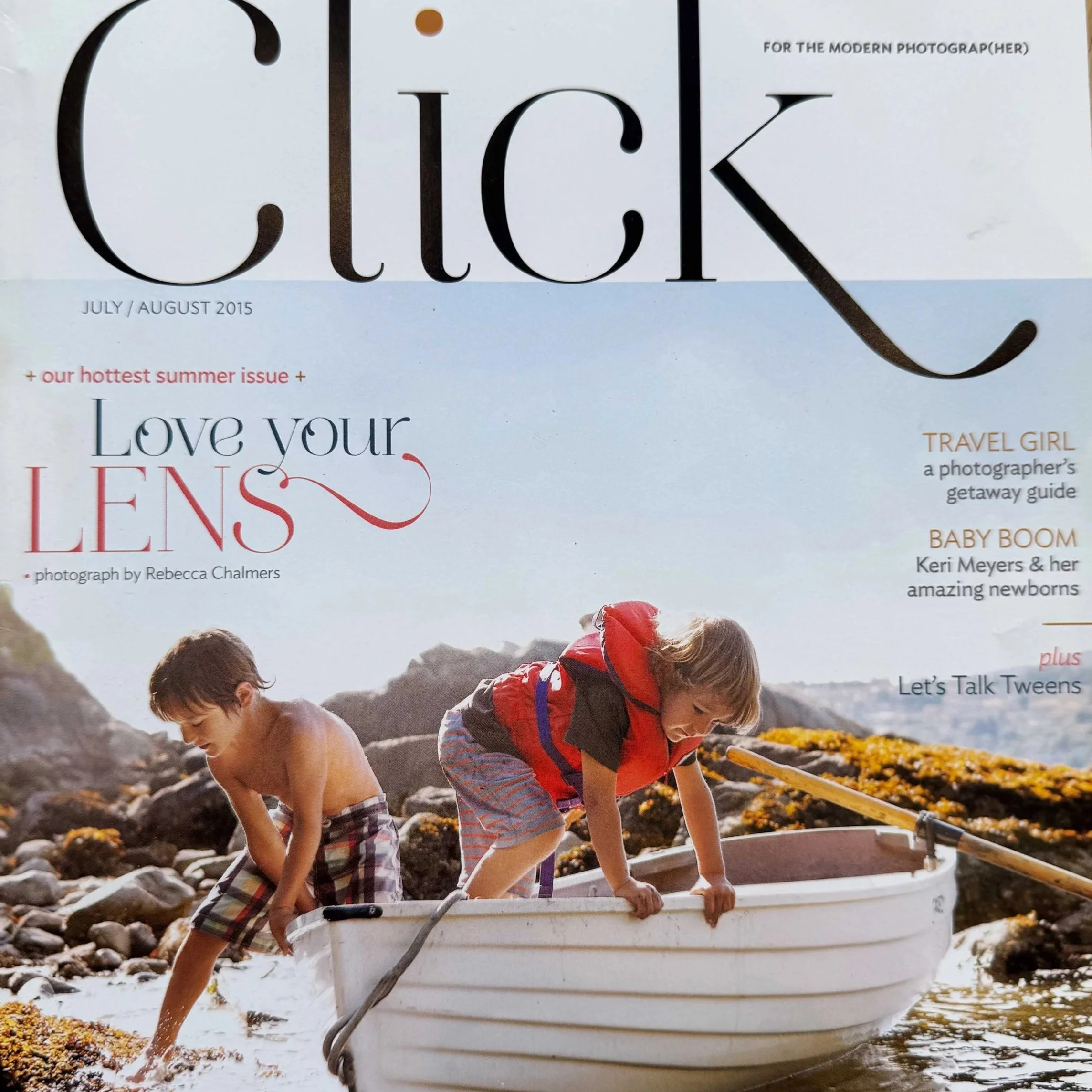 Two young boys in casual clothing leaning over the side of a rowboat on a rocky shoreline, with a focus on their upper bodies and the boat.