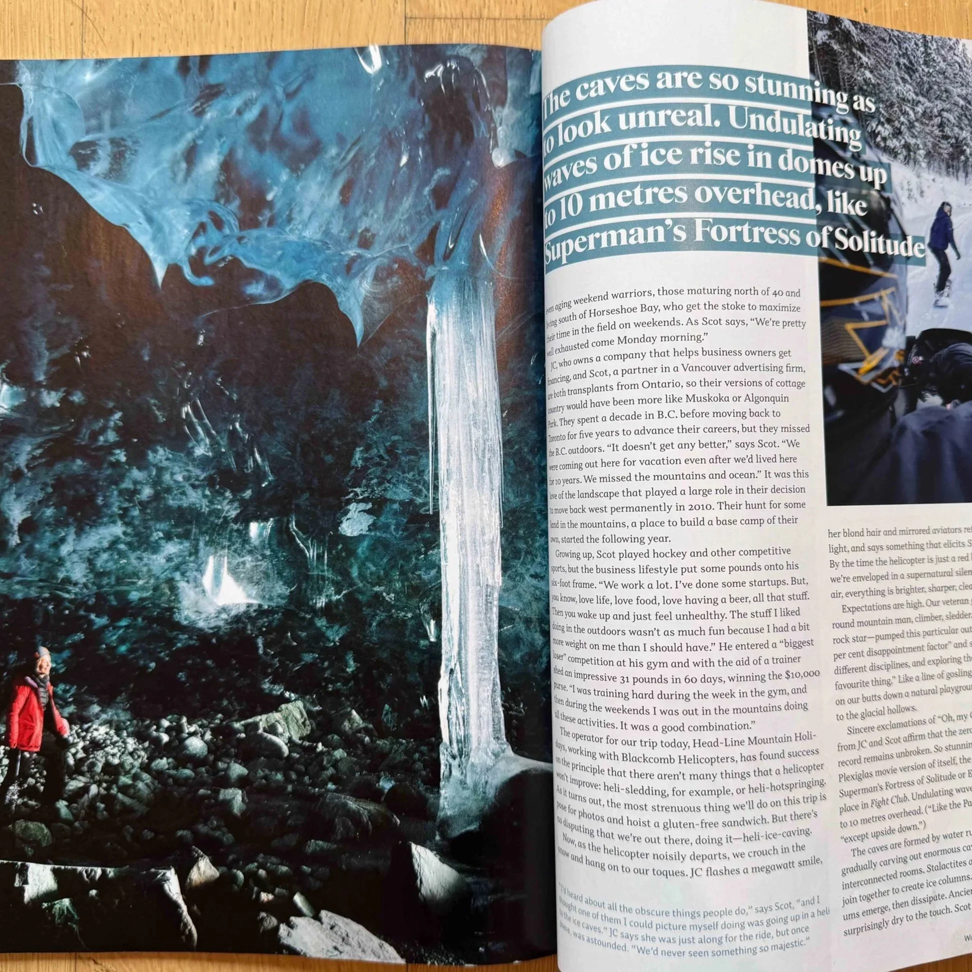 Photo of an icy cave with ice formations and a rocky floor. Two people are visible, one in a red jacket and another in a blue jacket, exploring inside the cave.