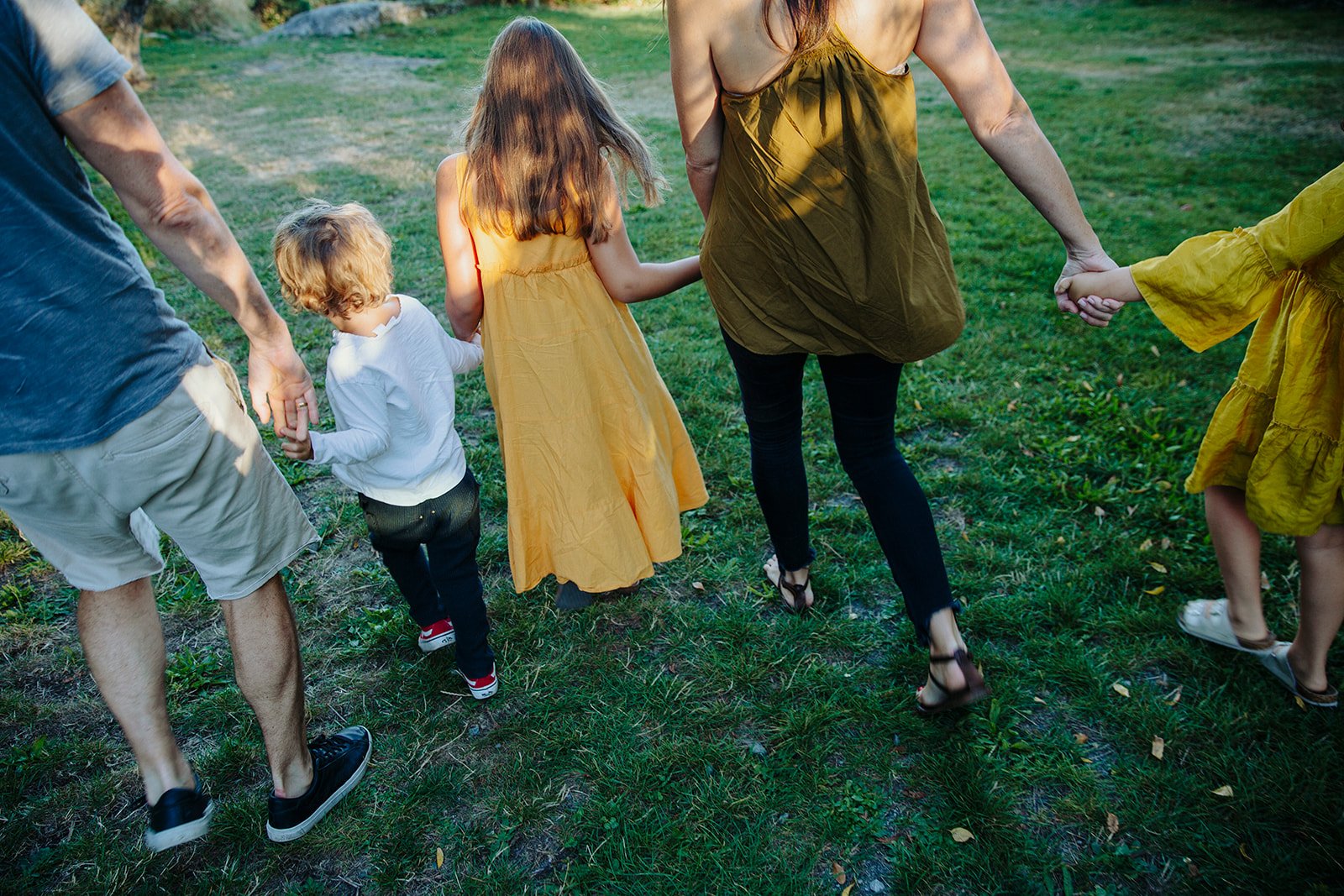 Family holding hands and walking on grass in a park during daytime