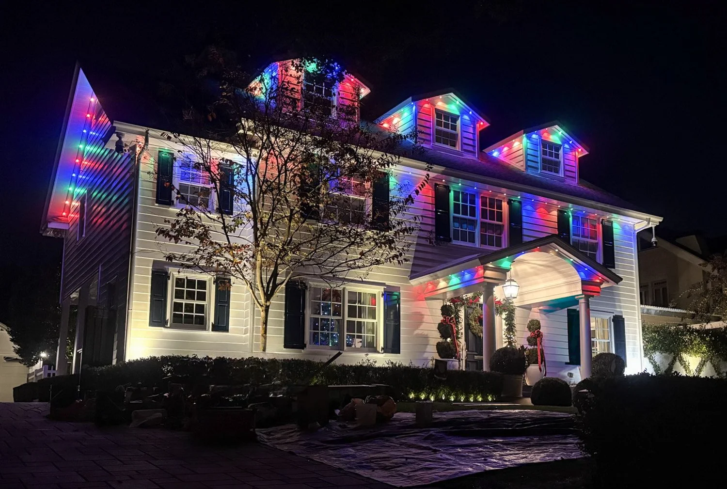 Multi-color permanent LED lighting on a colonial-style home's roofline, dormers, and entry in Los Angeles