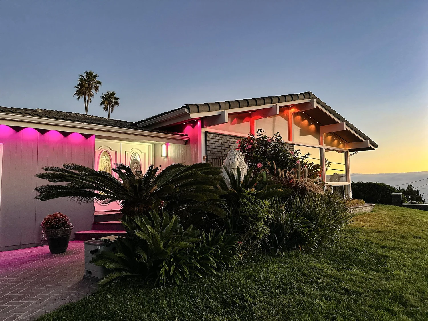 Permanent color-changing LED lighting on a mid-century home in Los Angeles at sunset, pink and orange eave lighting