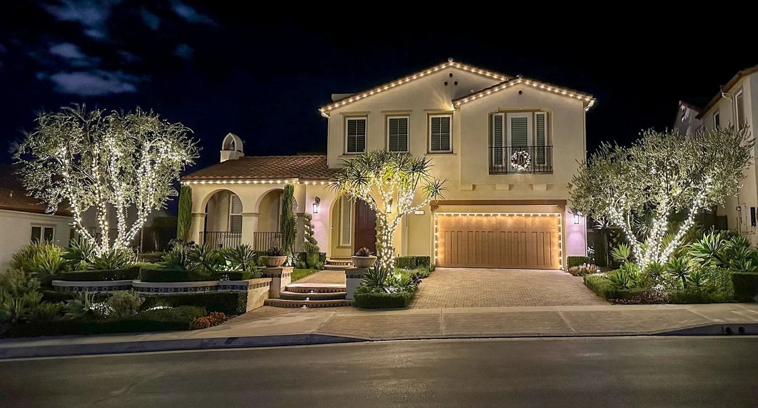 Two-story home with tree-wrapped holiday lights and lit garage, Los Angeles