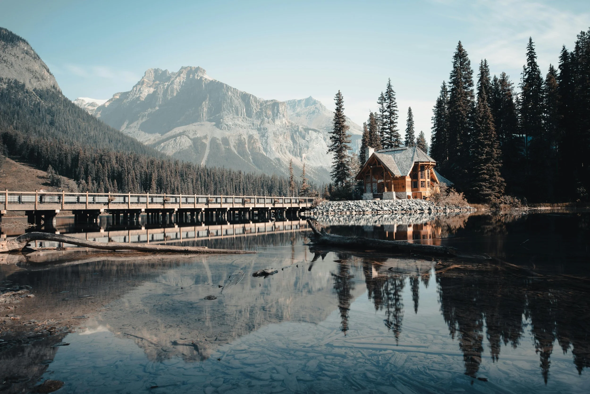 Solitude cabin surrounded by a clear lake and snow-covered mountains in Yoho National Park