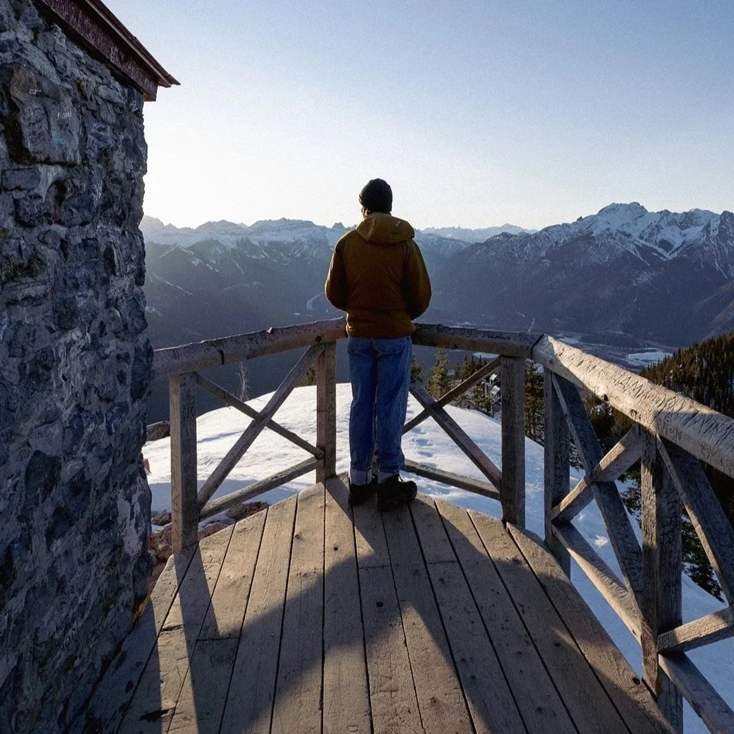 Hiker overlooking the snow-capped mountain range in Banff, AB