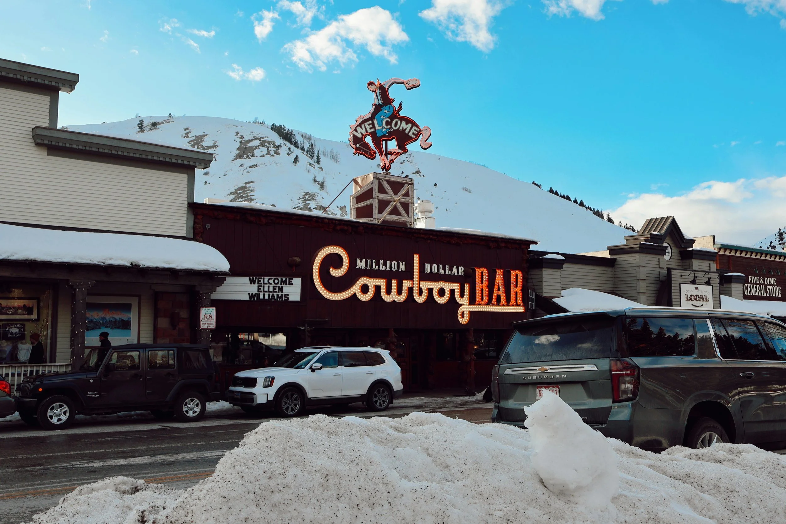 A mini-bulb lit sign titled "Cowboy BAR" on the side of a red building in Jackson Hole, WY