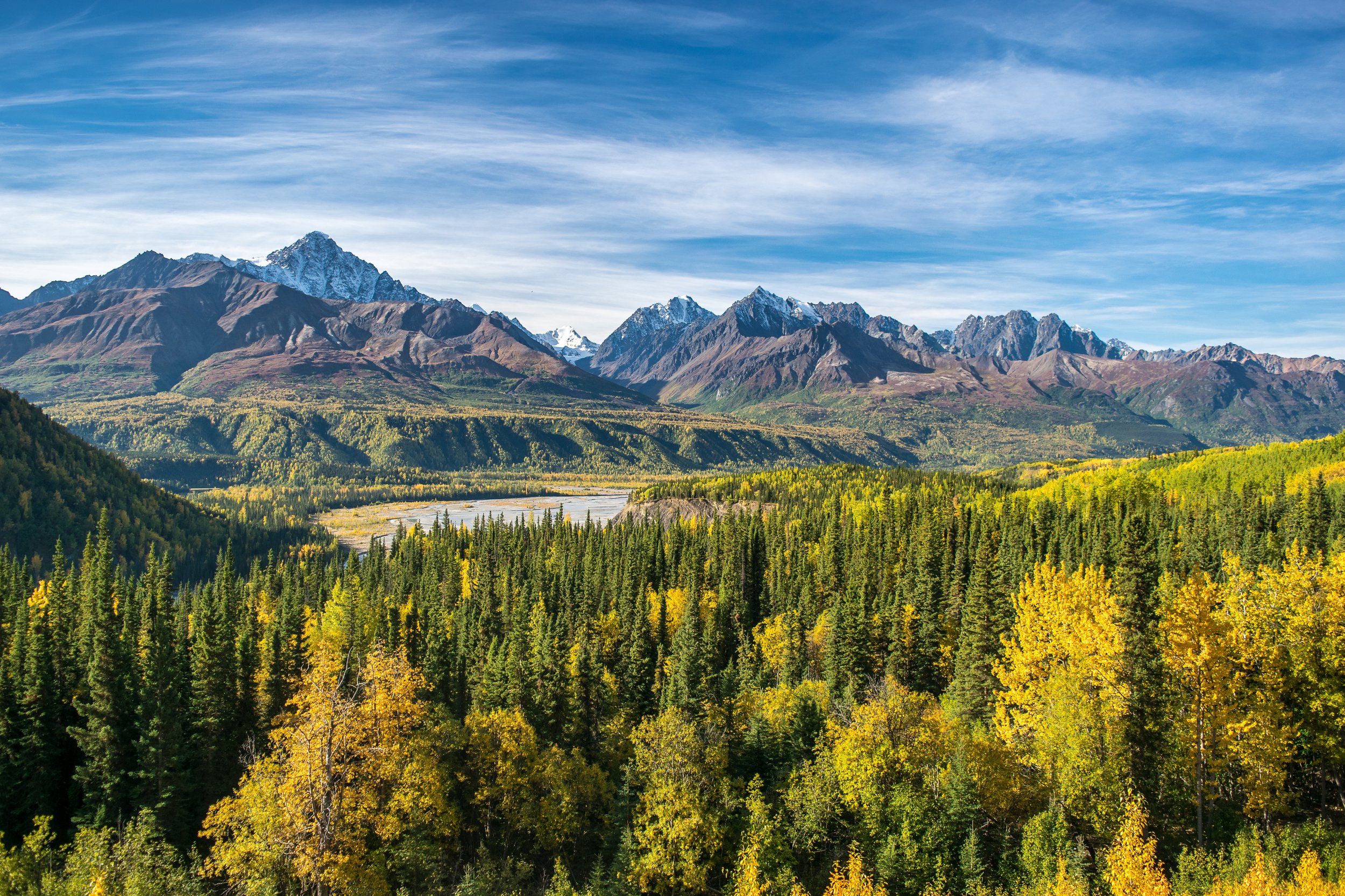 Green and yellow foliage surrounded by mountains and a river