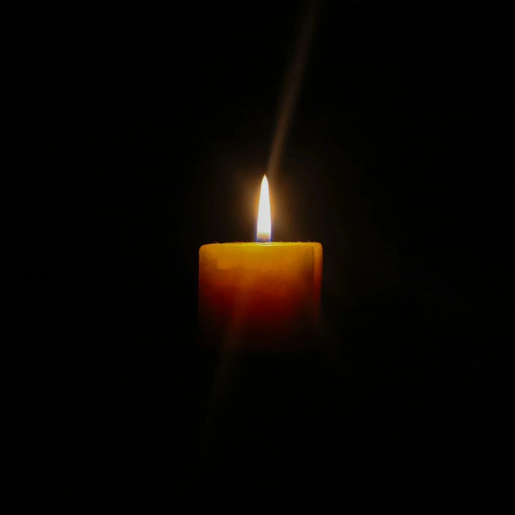 yellow lit candle in the dark