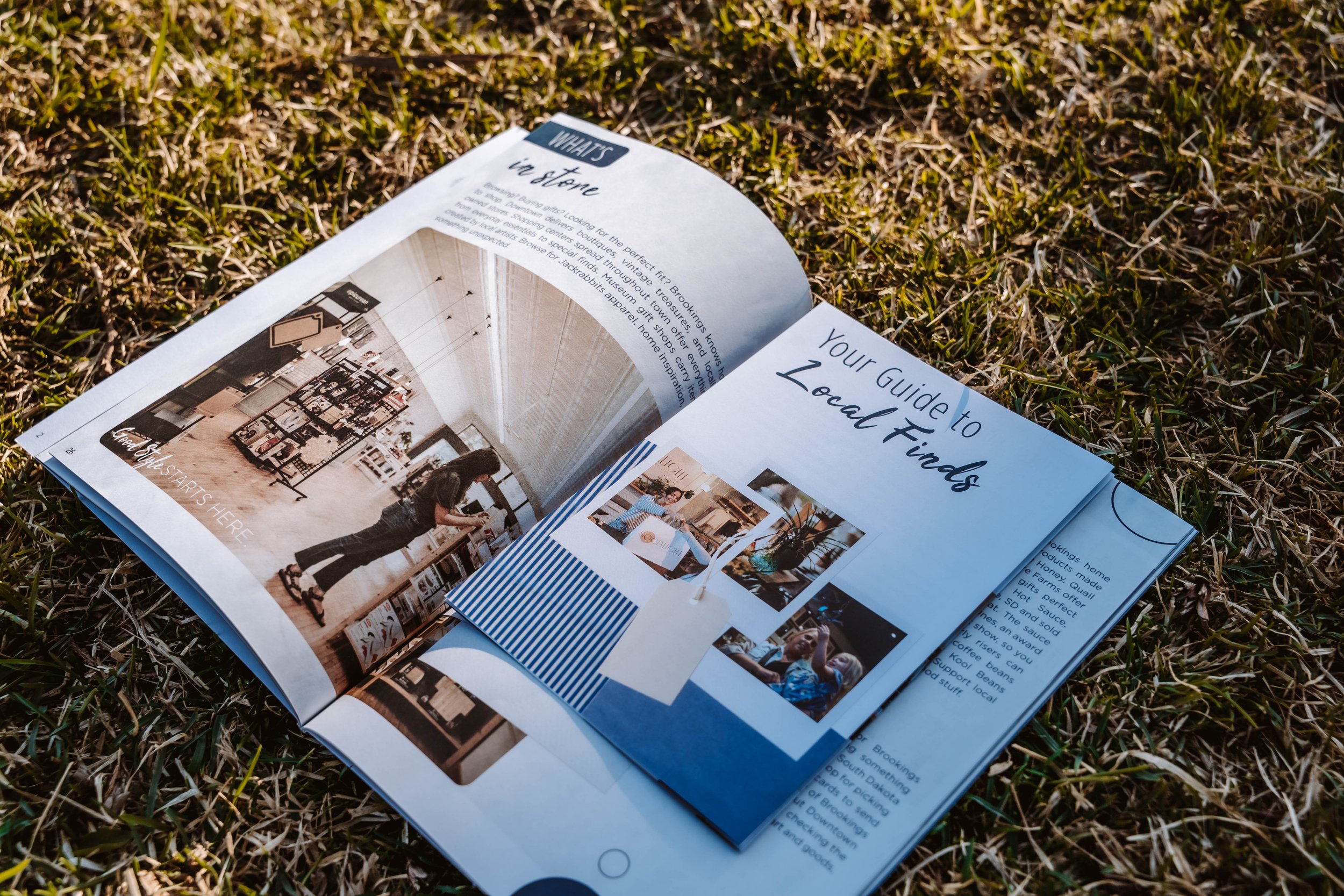 Open magazine or brochure laying on grass, featuring interior decorating images and text about local finds.