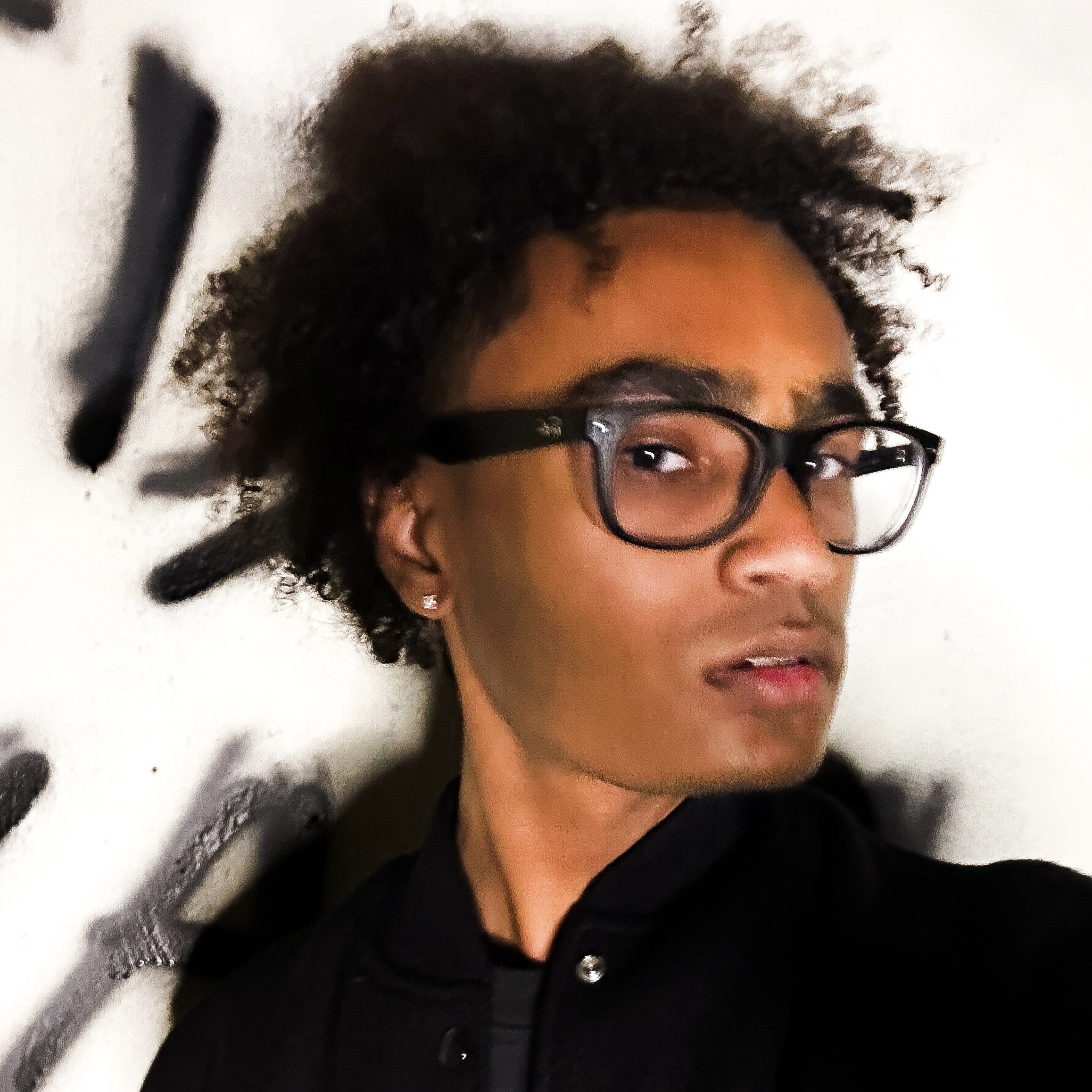 R.I.P. Ali posing in front of the camera with graffiti in the background.