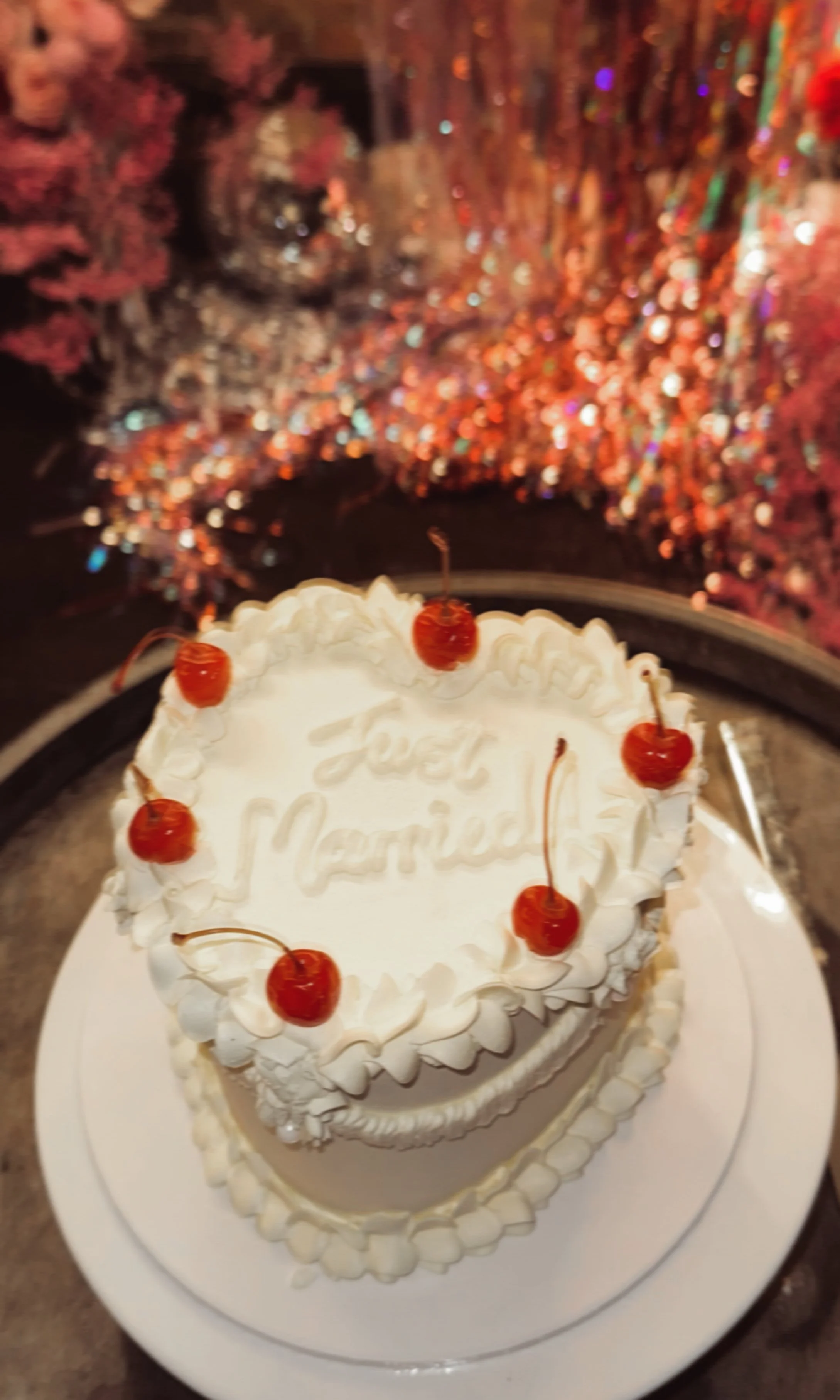 A white cake with whipped cream and cherries on top, with a message reading 'Just Married'.